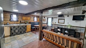 Una cocina con salpicadero de piedra, armarios de madera y una isla integrada. Hay una zona de comedor con un banco y una mesa.