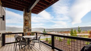 Une terrasse en bois avec un pilier en pierre, une table et des chaises.
