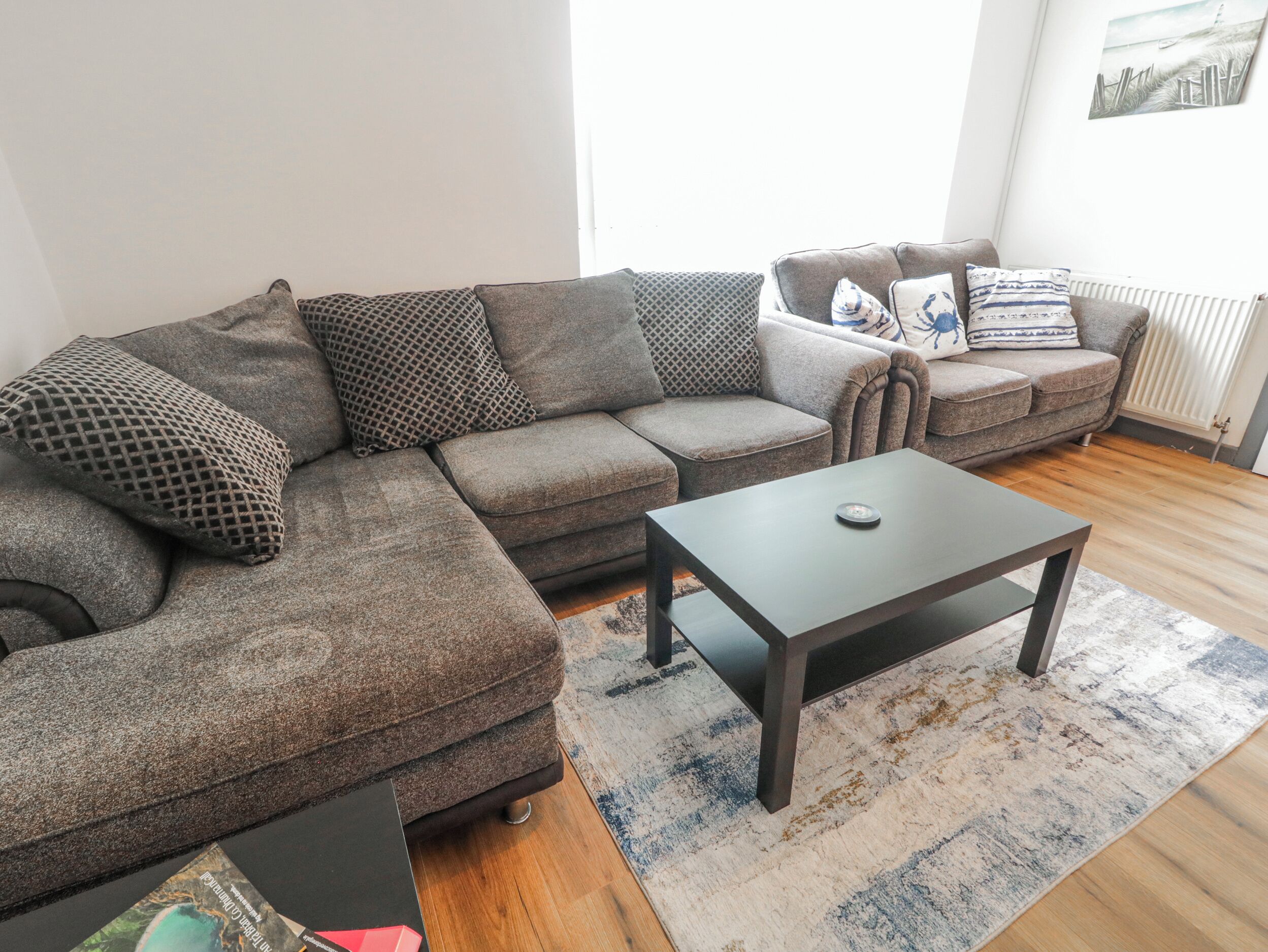 Una sala de estar con un sofá modular, una mesa de centro y una alfombra estampada.