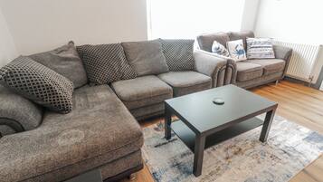 Una sala de estar con un sofá modular, una mesa de centro y una alfombra estampada.