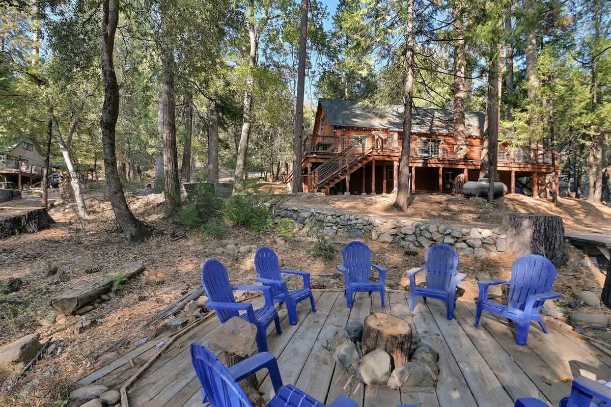 Een blokhut met een terras en blauwe Adirondack-stoelen.