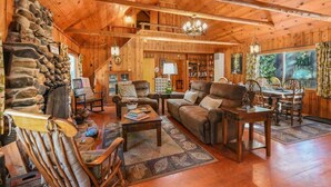 L’intérieur d’un chalet confortable, avec une cheminée en pierre, des meubles en cuir et un coin repas.