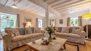 A cozy living room with two beige sofas, a wooden coffee table, and a vase of flowers.
