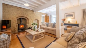 A cozy living room with a brick fireplace, a wooden coffee table, and a comfortable sofa.