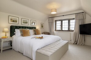 A neatly arranged bedroom with a bed, bedside table, lamp, and a television.