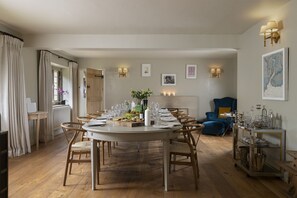 A dining room with a round table set for six, surrounded by wooden chairs.