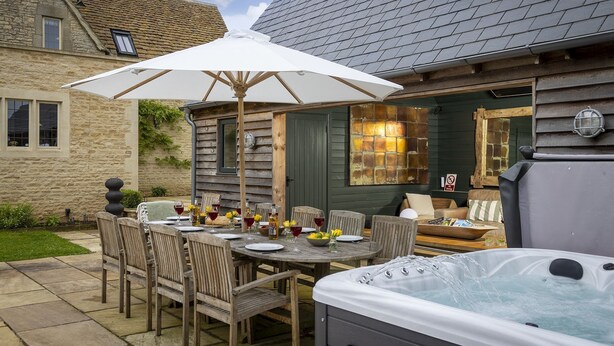 Une terrasse en bois avec une table à manger, des chaises et un jacuzzi.