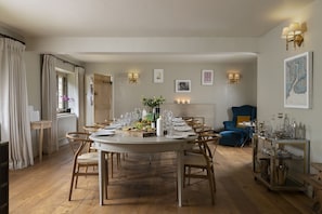 A dining room with a round table set for six, surrounded by wooden chairs.