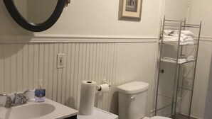 Un baño con lavamanos blanco, espejo, inodoro y perchero para toallas.