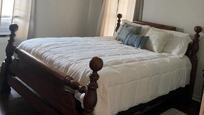 Un dormitorio con cama de madera, ventilador de techo y un cuadro con flores en la pared.