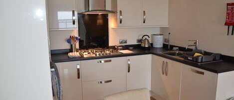 A modern kitchen with white cabinets, stainless steel appliances, and a black countertop.