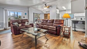 Ein geräumiges Wohnzimmer mit einer Ledersofa, einem Glastisch und einem Essbereich mit Holztisch und Stühlen.