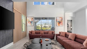 A modern living room with a large window, two sofas, a coffee table, and artwork on the walls.