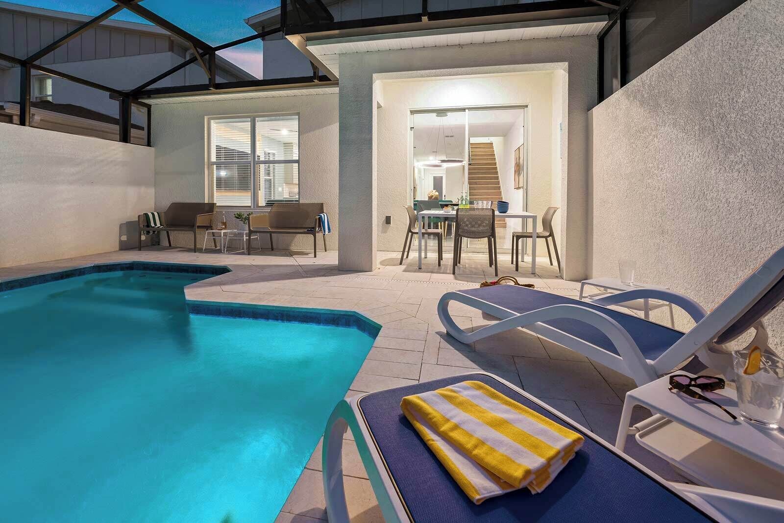 Une piscine entourée d’un patio couvert, avec des chaises longues et une table.