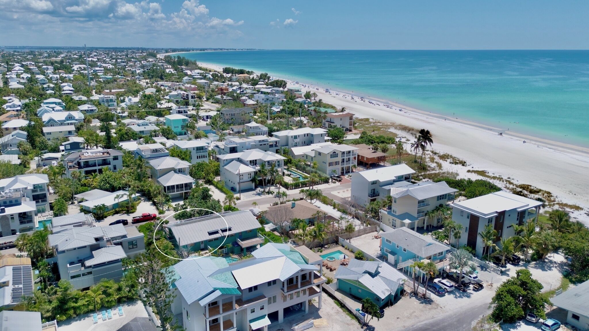 A coastal residential area with modern houses, a beach, and clear blue waters.
