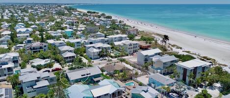 A coastal residential area with modern houses, a beach, and clear blue waters.
