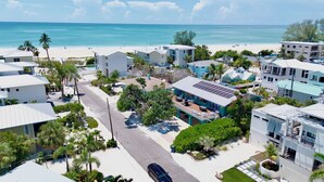 A coastal residential area with modern houses, a beach, and a clear view of the ocean. - Emerald Shores East! Walk to Beach! (Anna Maria)