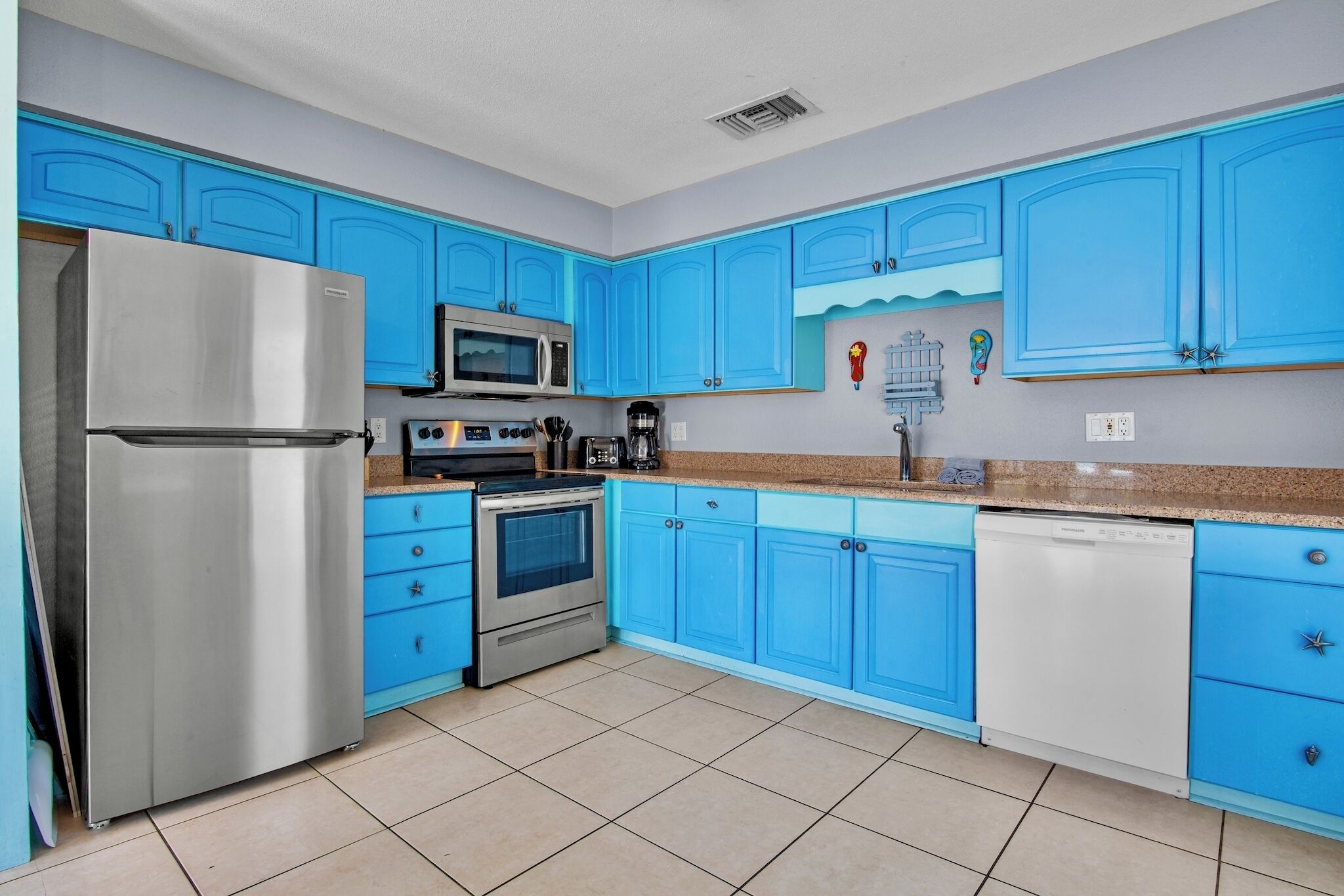 A kitchen with blue cabinets, stainless steel appliances, and a tiled floor.