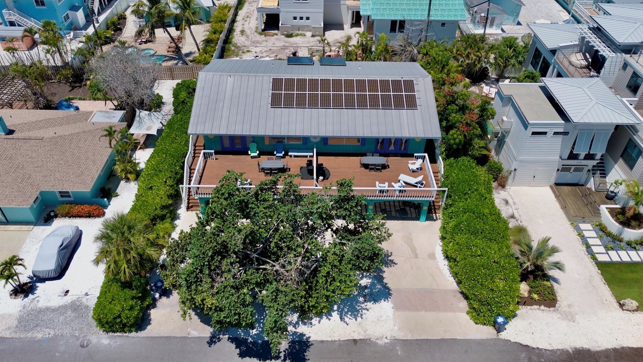 Ein Luftbild eines modernen Gebäudes mit einer Solaranlage auf dem Dach, einer überdachten Außenbereich-Sitzgelegenheit und einem gepflegten Garten.