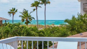A beachfront property with a view of the ocean, palm trees, and a white railing. - Emerald Shores East! Walk to Beach! (Anna Maria)