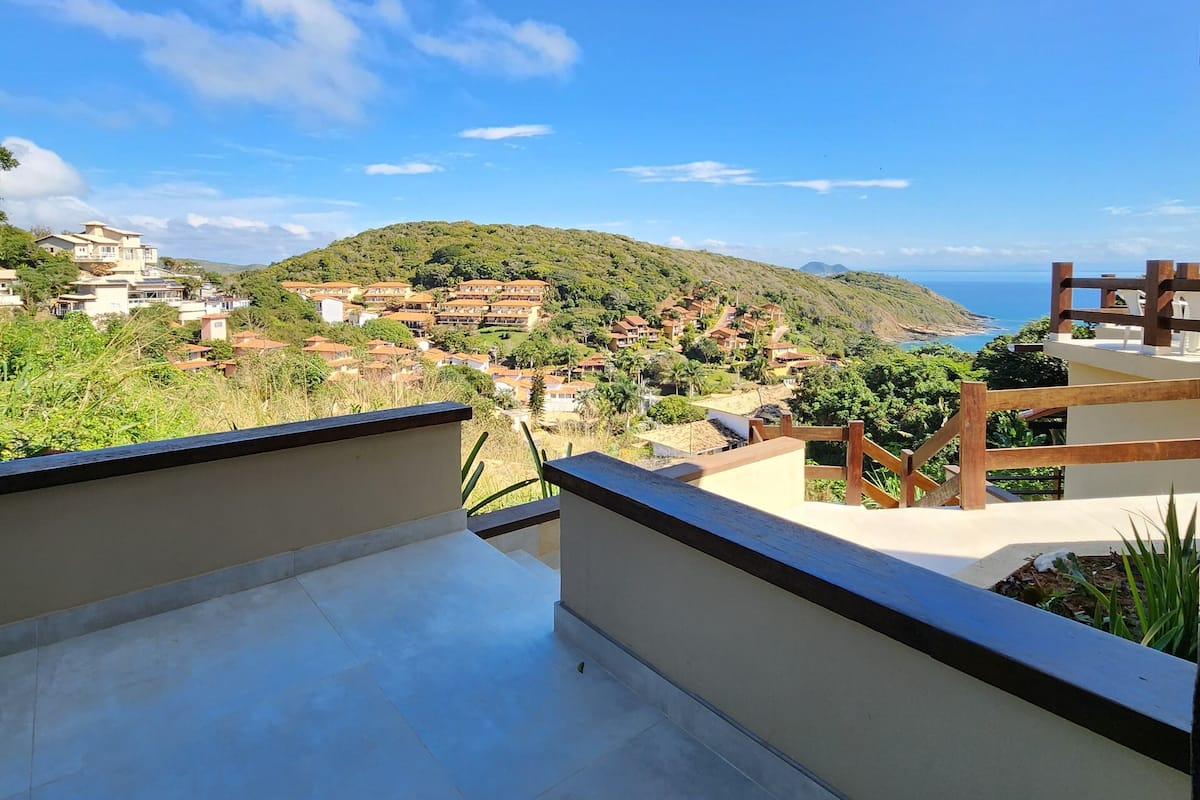 A balcony with a view of a hillside village and the sea.