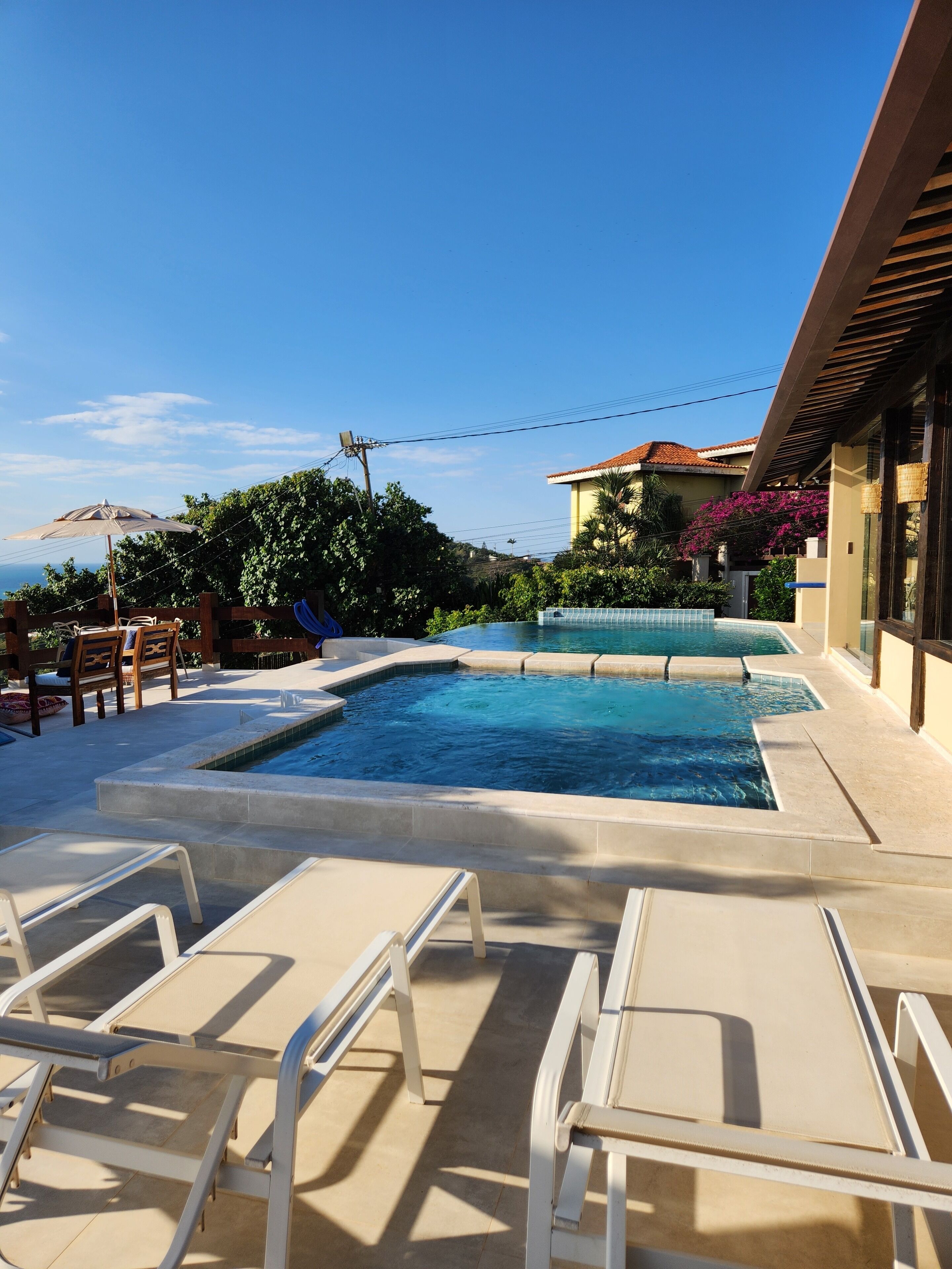 A swimming pool with lounge chairs and a view of a building with a tiled roof.
