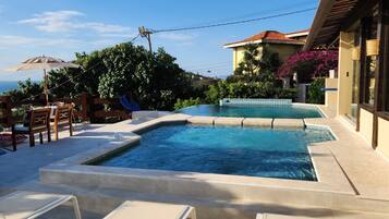 A swimming pool with lounge chairs and a view of a building with a tiled roof.