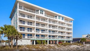 Un hôtel à plusieurs étages, doté de balcons, situé près d’une plage.