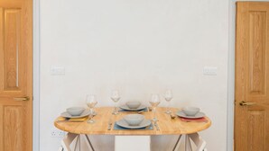 Mesa de comedor dispuesta con cuencos, platos y copas de vino, ubicada entre dos puertas de madera.