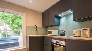 Una cocina moderna con armarios oscuros, microondas, hervidor y tostadora.