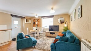 A living room with a sofa, TV, and dining area. - Host Stay Moorland Cottage (York)