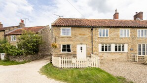A stone cottage with a white picket fence, a gravel driveway, and a small garden. - Host Stay Byre Cottage (York)