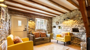 A cozy room with stone walls, a fireplace, a sofa, and two armchairs. - Host Stay Byre Cottage (York)