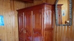 Una habitación con paneles de madera, una cama, un armario y un espejo.