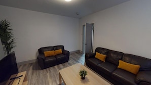 Ein modernes Wohnzimmer mit zwei Ledersofas, einem Holztisch und einem Fernseher.