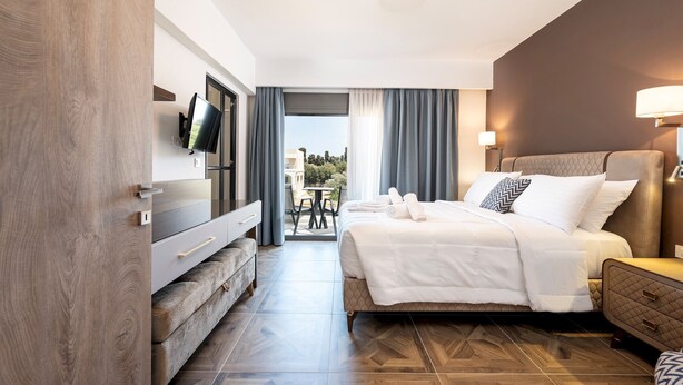 Une chambre d’hôtel moderne dotée d’un grand lit, d’une télévision, d’un bureau et offrant une vue sur l’extérieur.