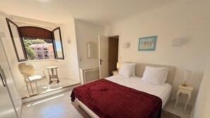 Een slaapkamer met een bed, een stoel, een tafel en een raam.