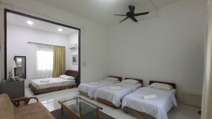 A hotel room with two single beds, a sofa, a glass-top table, and a ceiling fan. - Kurau Inn  Farmstay (Kuala Kurau)
