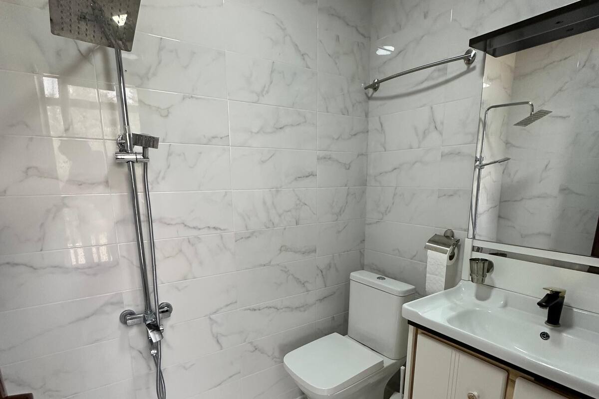 A bathroom with a shower, toilet, and sink.