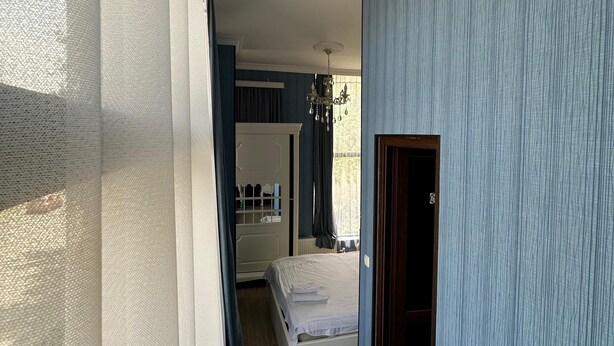 A bedroom with a bed, a dresser, and a window with curtains. - AİSİ HOTEL (Kutaisi)