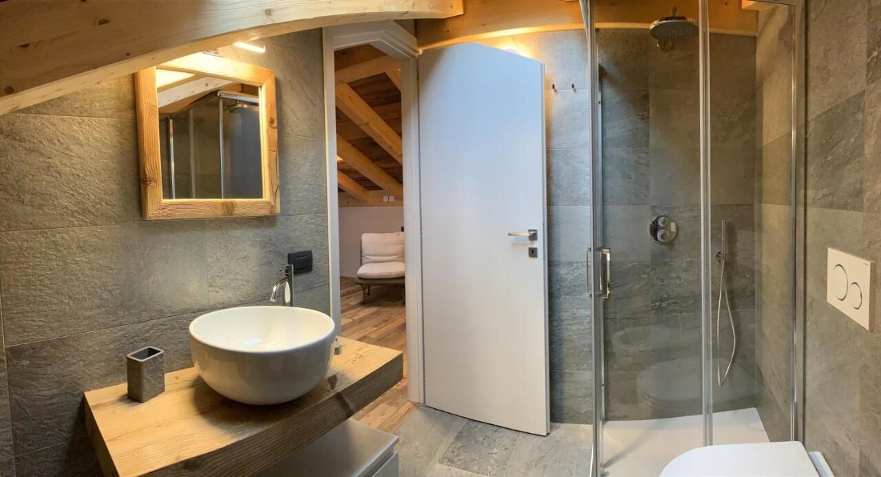 A modern bathroom with a large sink, a glass shower enclosure, and a wooden vanity.