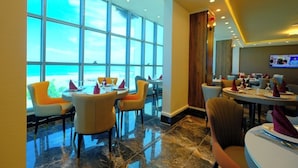 A restaurant with large windows, modern chairs, and a polished floor. - Hotel El Bey Jijel  (Jijel)