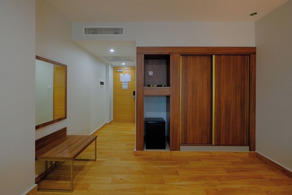 Um corredor com piso de madeira, um banco e um guarda-roupa de madeira com espelho.