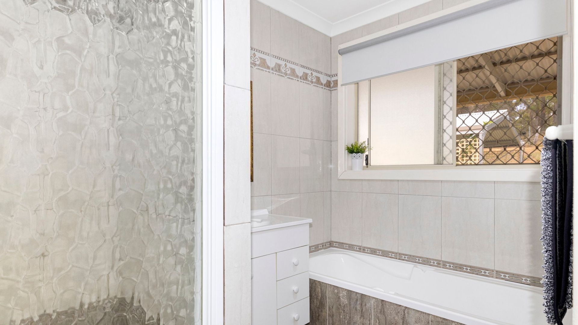 A bathroom with a white sink, a mirror, and a window with a view of a house.