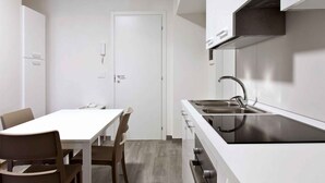 A modern kitchen with a white countertop, stainless steel sink, and wooden chairs. - Holiday apartment mit Klimaanlage und Pool (Pietra Ligure)
