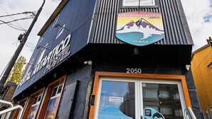 Un edificio con un cartel que dice 'Portal Antartico Hostel' y un mural de pingüinos en la puerta.