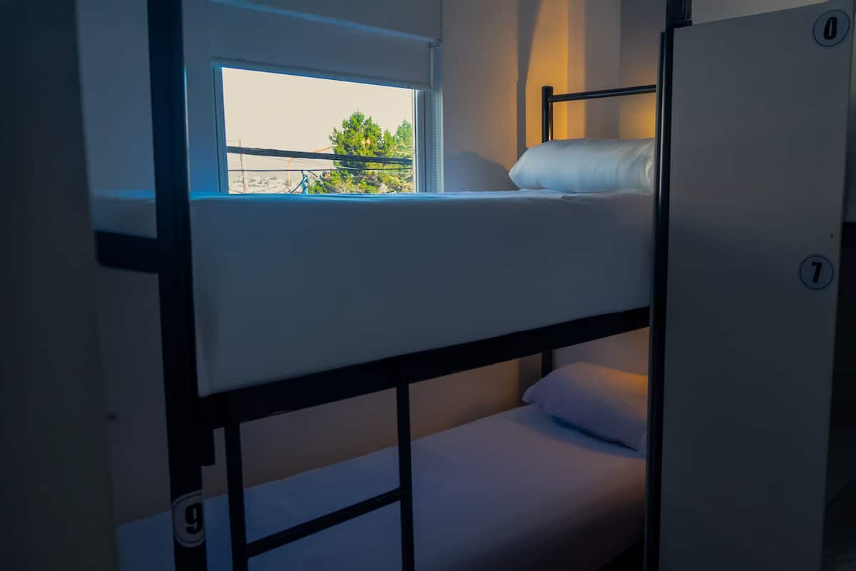 Habitación con literas, ventana, puerta y un número en la pared.