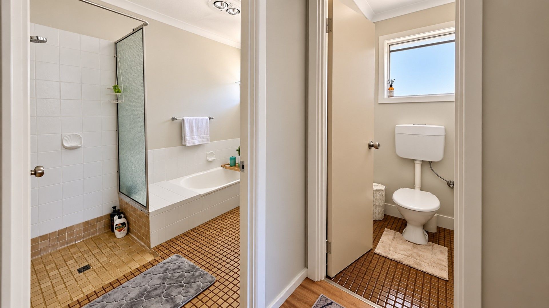 A bathroom with a shower, bathtub, toilet, and a window.