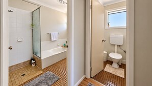 Un baño con ducha, bañera, inodoro y ventana.