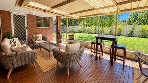 Un patio cubierto con muebles de mimbre, una mesa y sillas.